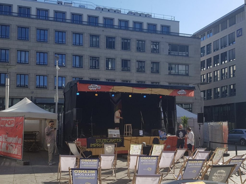 Bühne des Impro Kollektivs auf dem Kleinen Schlossplatz in Stuttgart mit Liegestühlen für das Publikum vor Beginn eines Improabends unter freiem Himmel.
